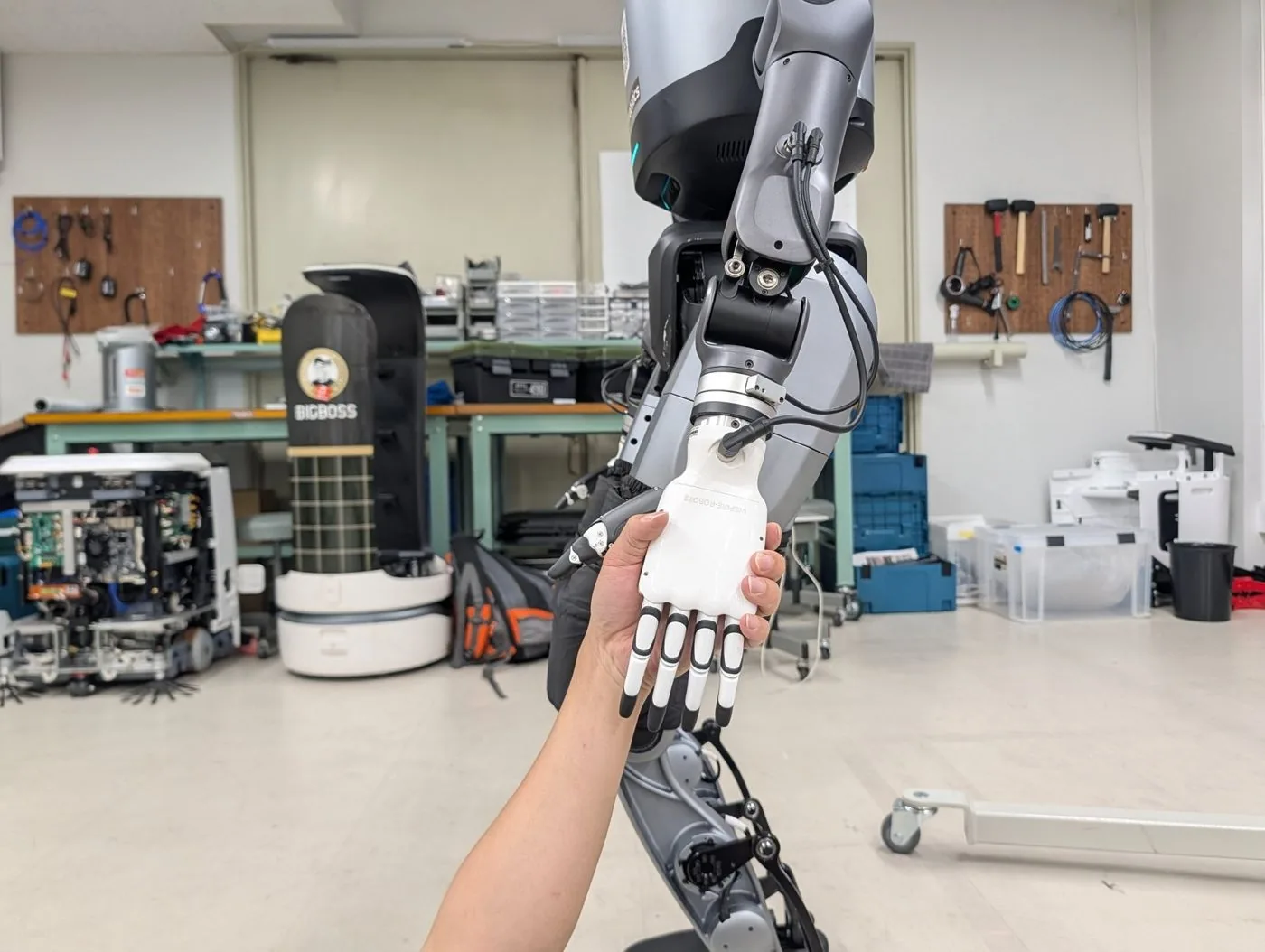 整備場でヒューマノイドの手に触れるエンジニア